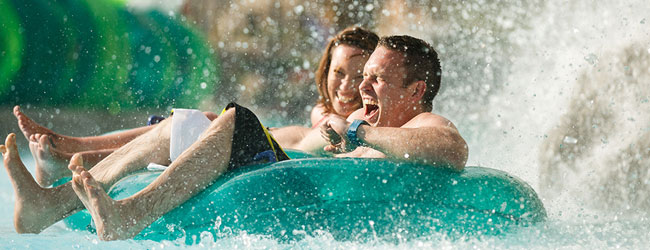 A couple going under one of the many waterfalls at the Downbound Float Trip Lazy River at Dollywood Splash Country Water Park wide